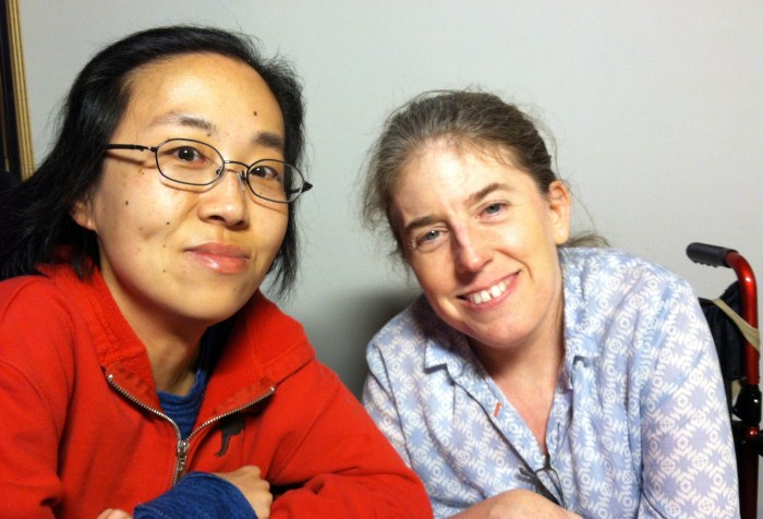 An Asian-American woman in a wheelchair is on the left and an white woman in a wheelchair is on the right.